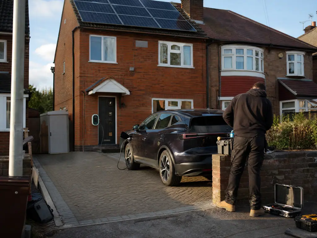 Electric car charging on a driveway with solar panels on the roof above, Birmingham